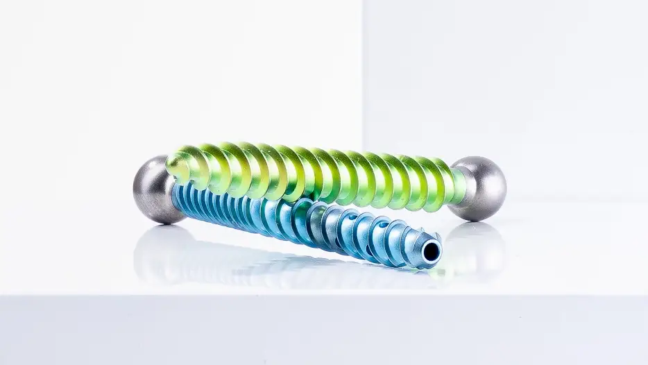 Green and blue specialty screws that are created at the TOMZ Corporation for use in medical devices.